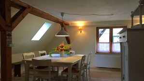 A dining area with a wooden table and chairs, a flower vase, and a skylight. - Apartment Ida up to 6 people (Stuer)