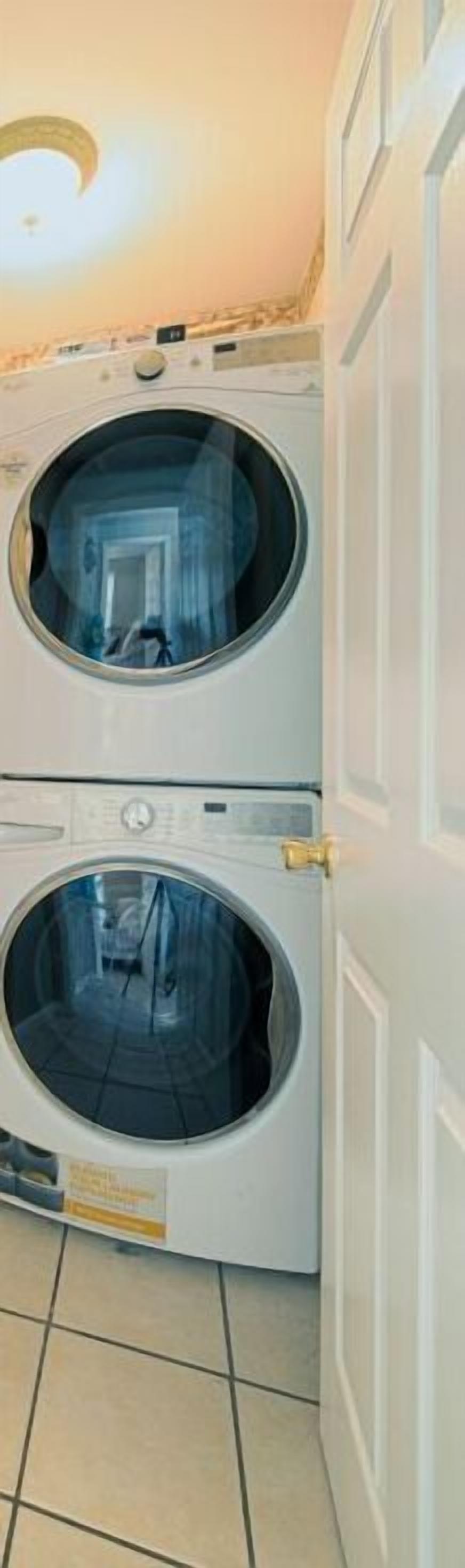 A laundry room with two stacked front-loading washing machines and a closed door.