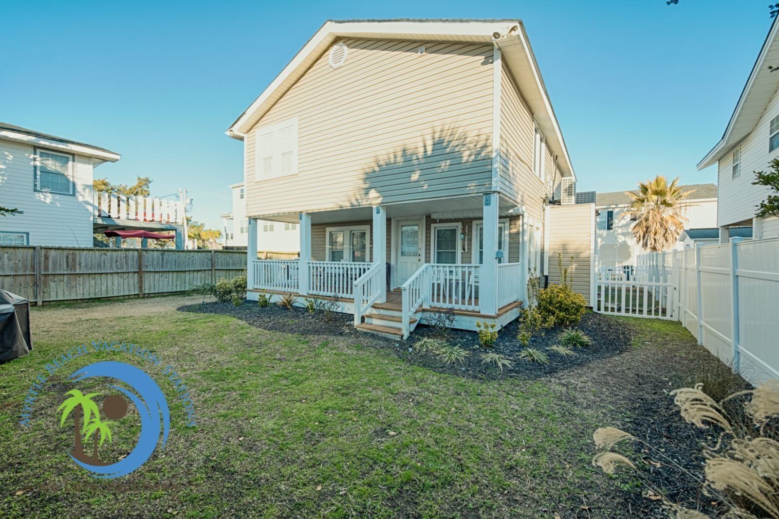 A two-story house with a front porch and a fenced backyard.