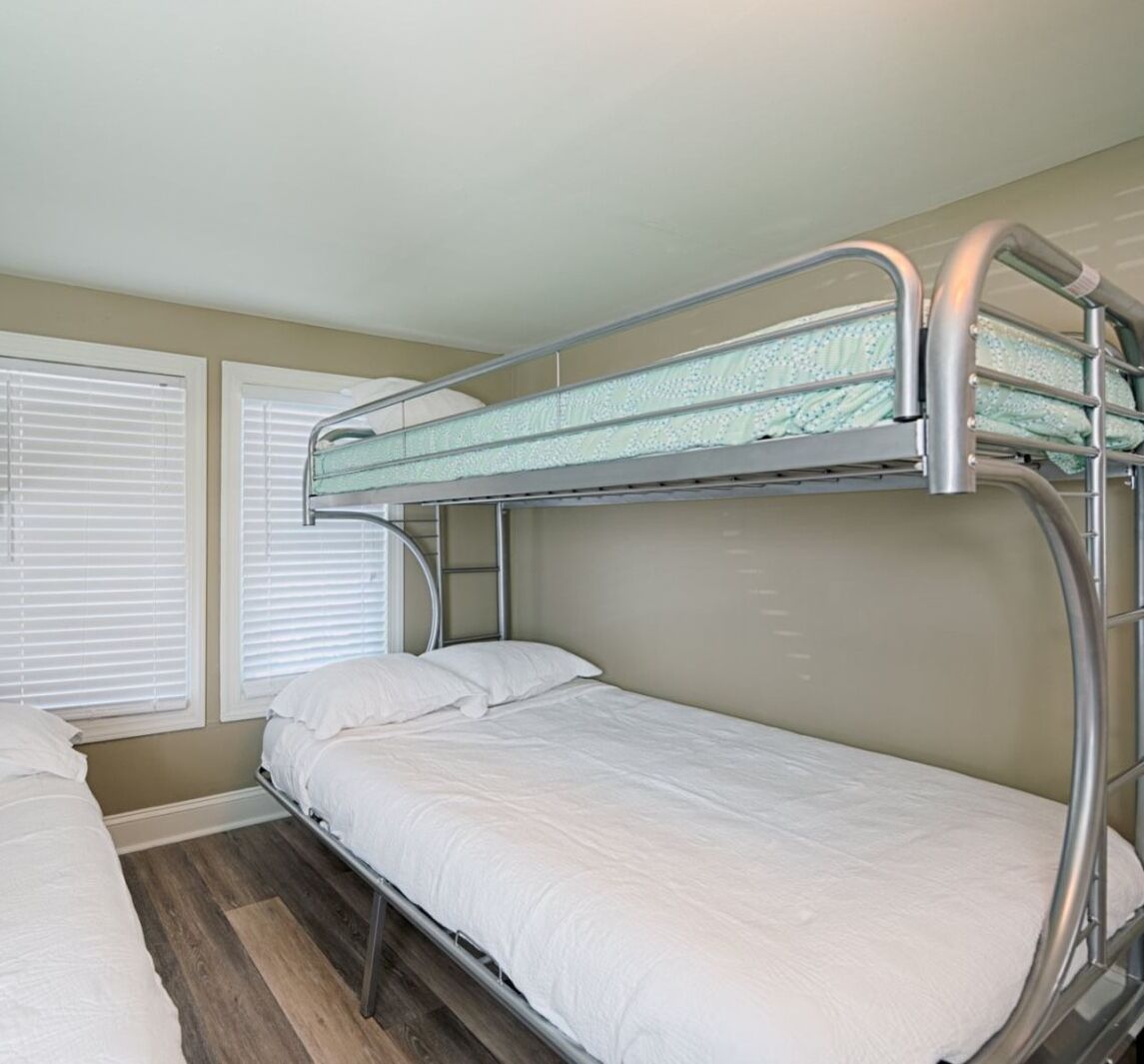 A bunk bed room with a window and a door.