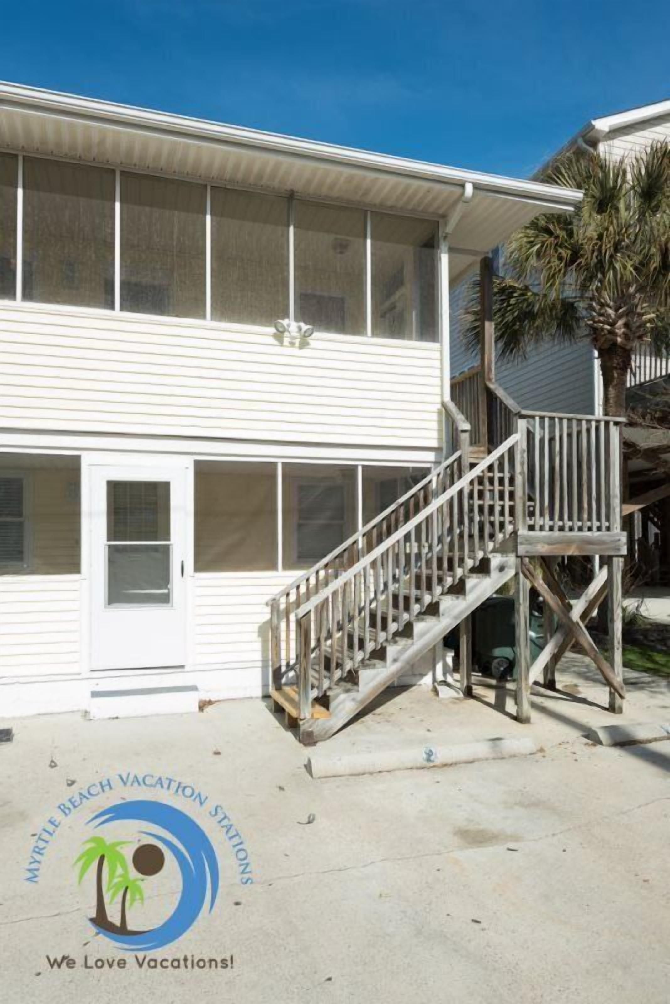 A two-story building with a wooden staircase leading to a deck.
