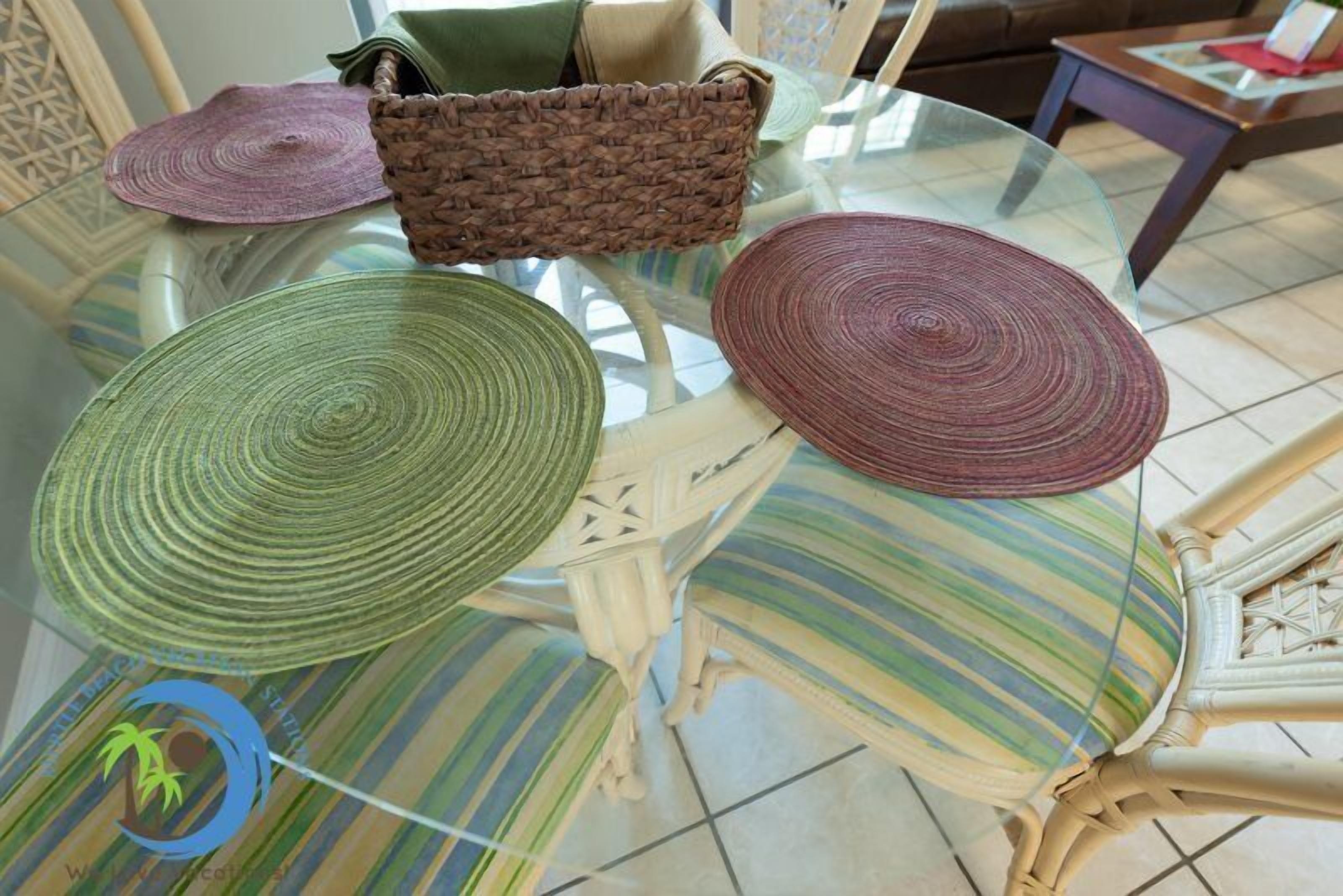 A glass table with woven placemats and a striped chair.