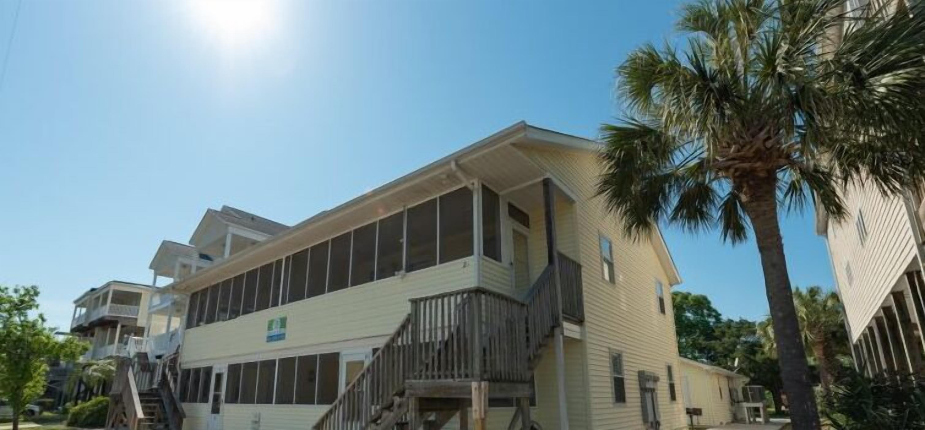 A multi-story building with a flat roof and large windows, surrounded by palm trees.