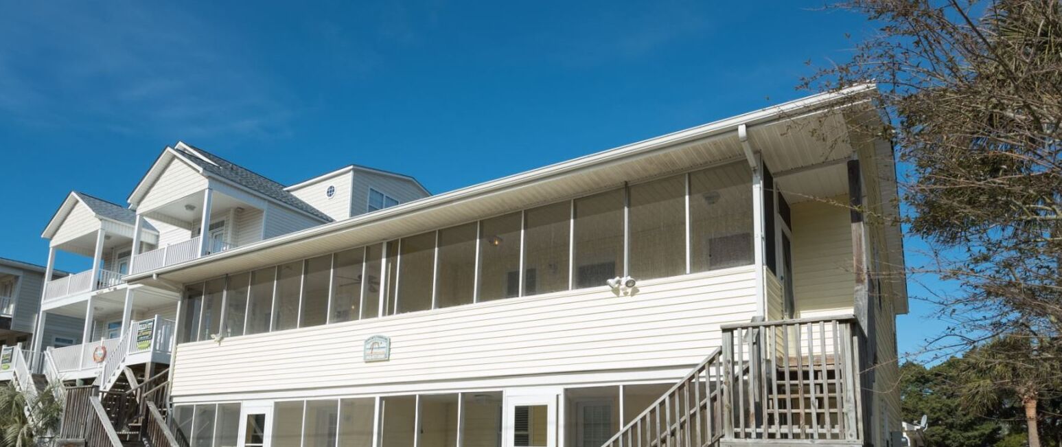 A large, white, two-story building with multiple balconies and large windows.