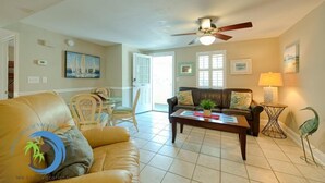 A spacious living room with a leather sofa, a coffee table, and a ceiling fan.