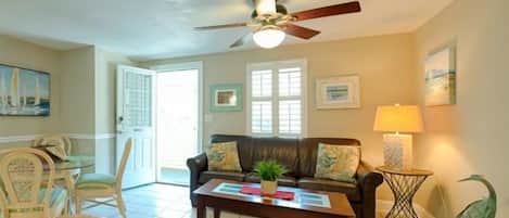A spacious living room with a leather sofa, a coffee table, and a ceiling fan.