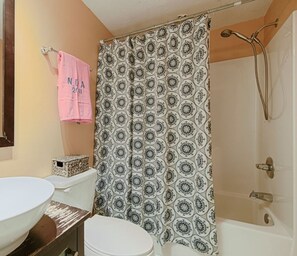 A bathroom with a patterned shower curtain, a white sink, and a toilet. - Windy Hill Villa A (North Myrtle Beach)