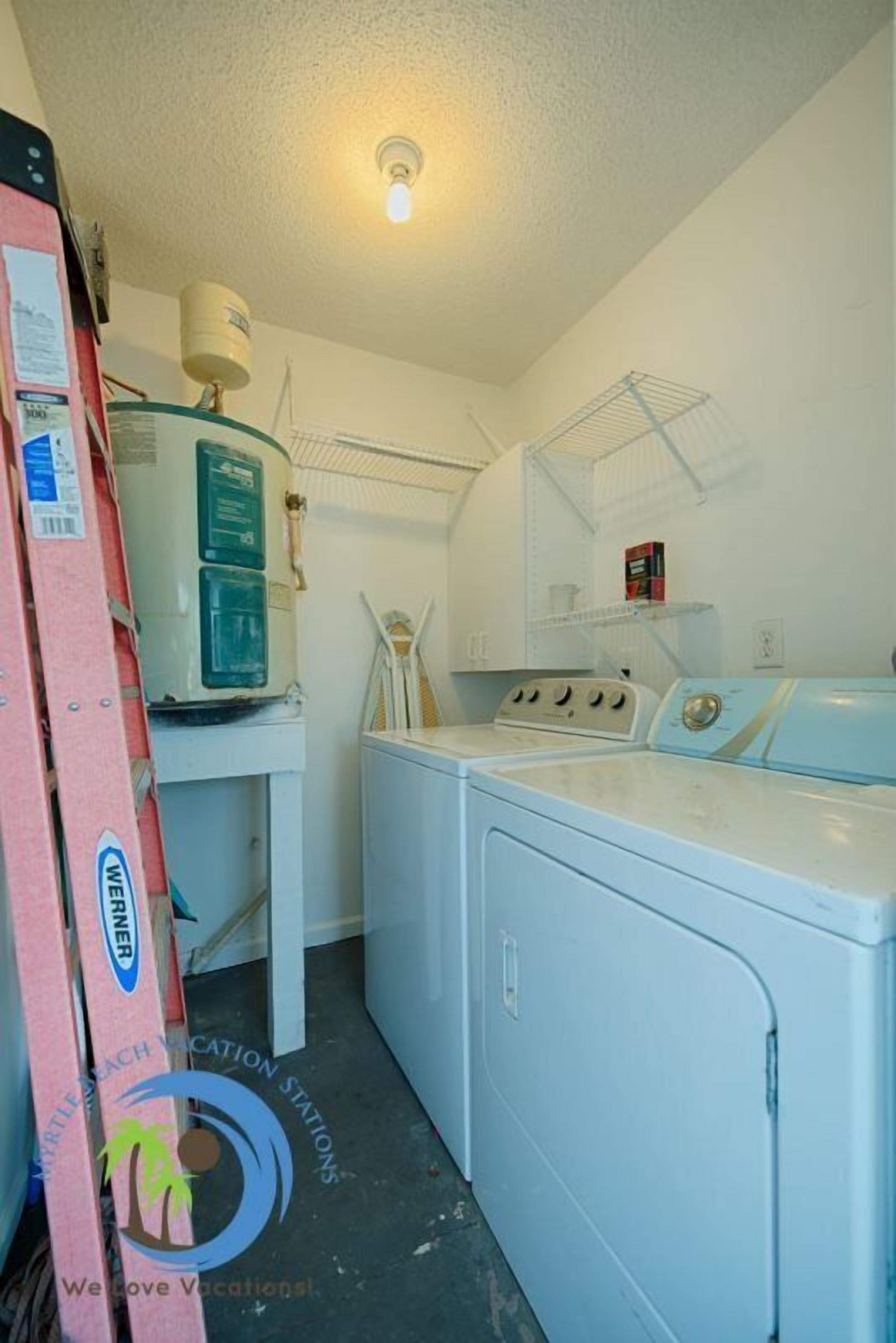 A laundry area with a washer and dryer, a water heater, and a shelf with items.