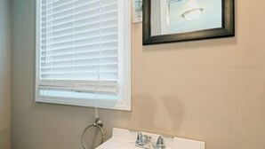 A bathroom with a white sink, wooden vanity, and a mirror with a black frame. - CG Efficiency (North Myrtle Beach)