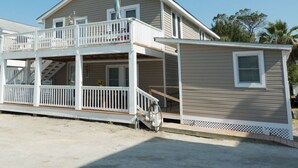 A two-story beach house with a balcony, a covered porch, and a small attached structure. - CG Efficiency (North Myrtle Beach)