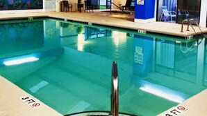 An indoor swimming pool with clear water, marked depth lines, and a lifeguard stand. - CG Efficiency (North Myrtle Beach)