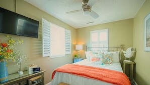Une chambre à coucher comprenant un lit, une table de chevet, une lampe et un téléviseur fixé au mur.
