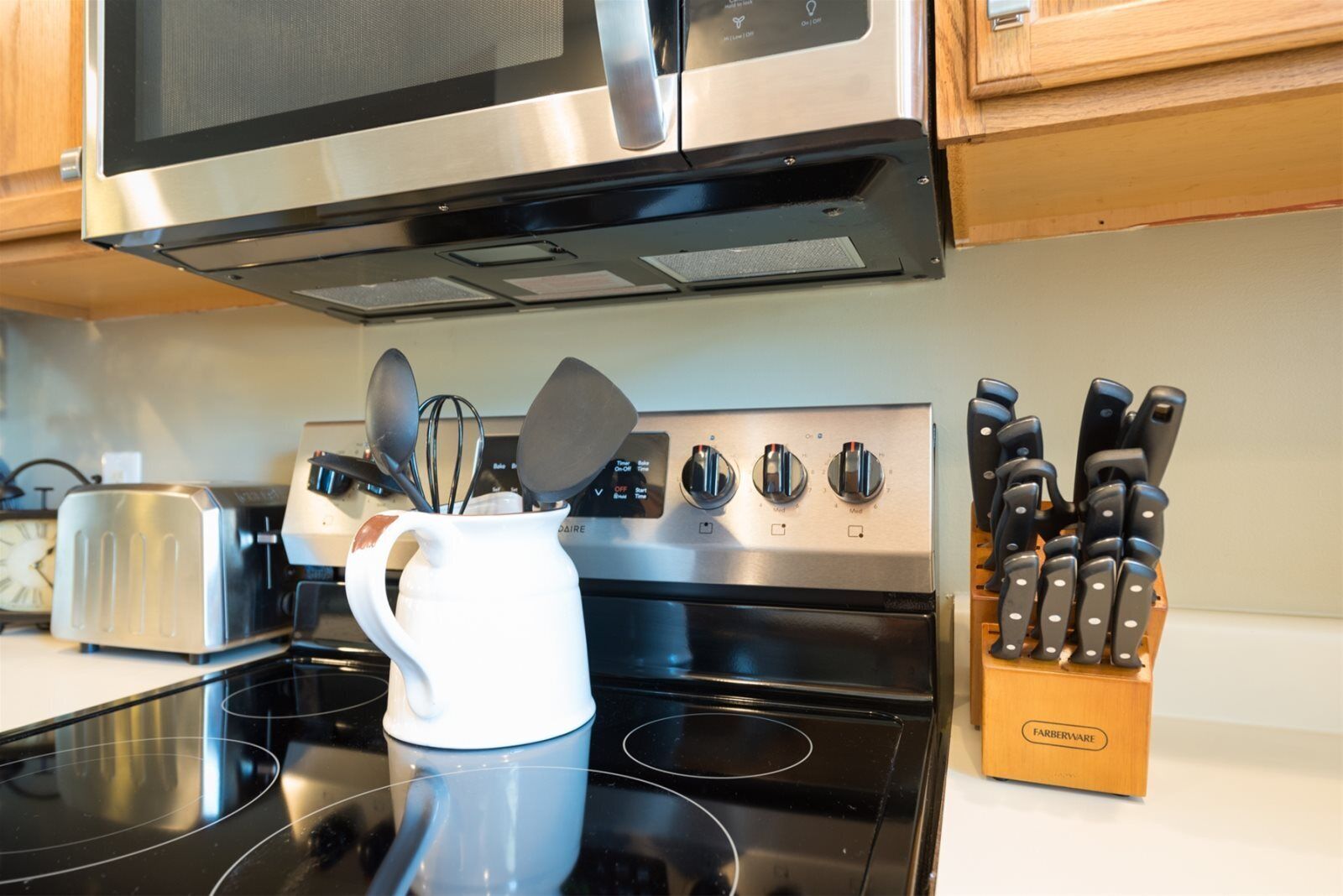 A kitchen with a stainless steel stove, a microwave, a toaster, and a knife block.