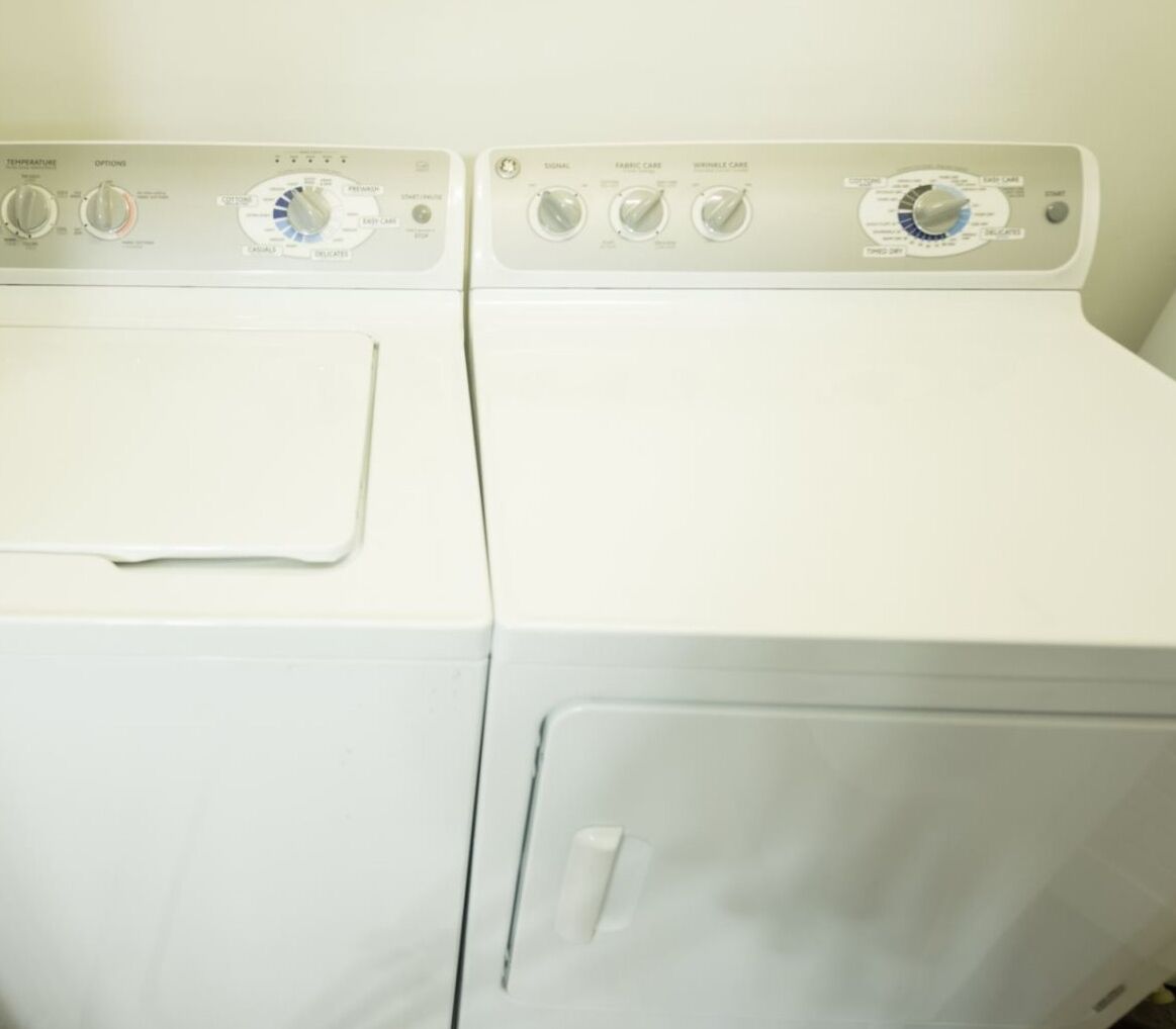 Una lavadora blanca de carga frontal con perillas para temperatura, opciones y configuraciones.