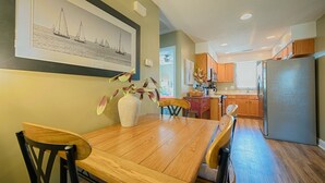 Un coin repas avec une table et des chaises en bois, un vase rempli de fleurs et un tableau encadré accroché au mur.