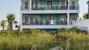 A two-story beachfront property with a covered balcony and a sandy pathway leading to the entrance. - "Be Still" - Oceanfront Home w/ Private Pool, 4 Bedrooms / 3.5 Bathrooms (Holden Beach)