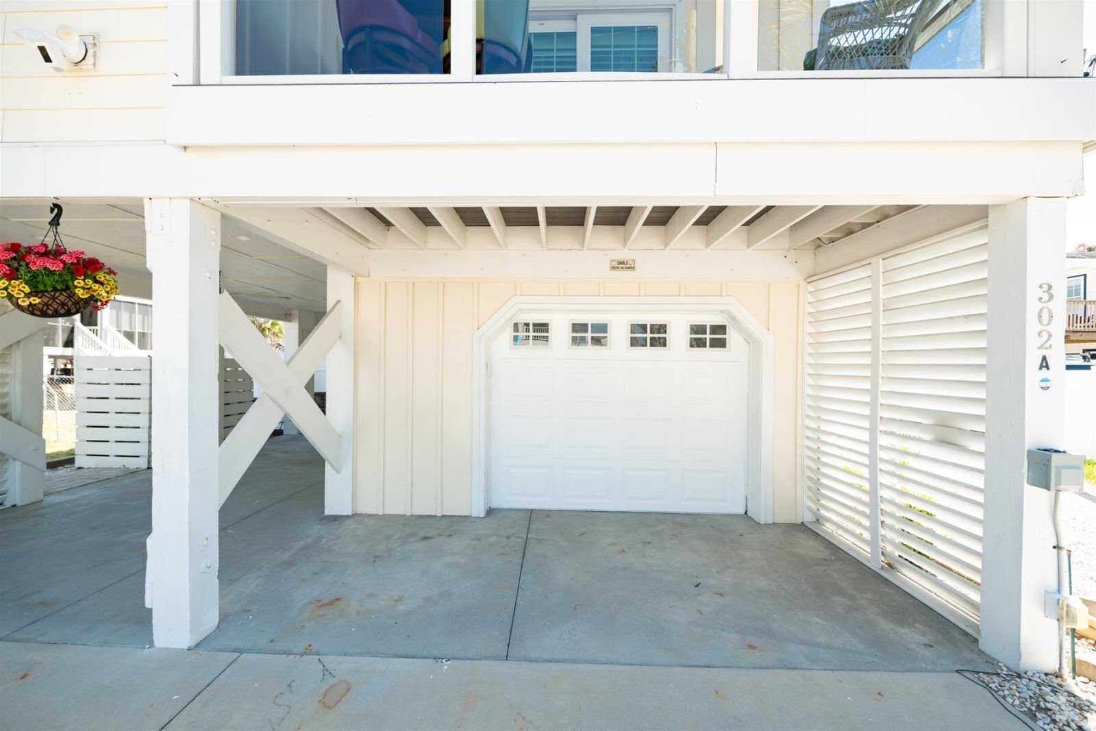 A garage with a white door, a covered entryway, and a white fence.