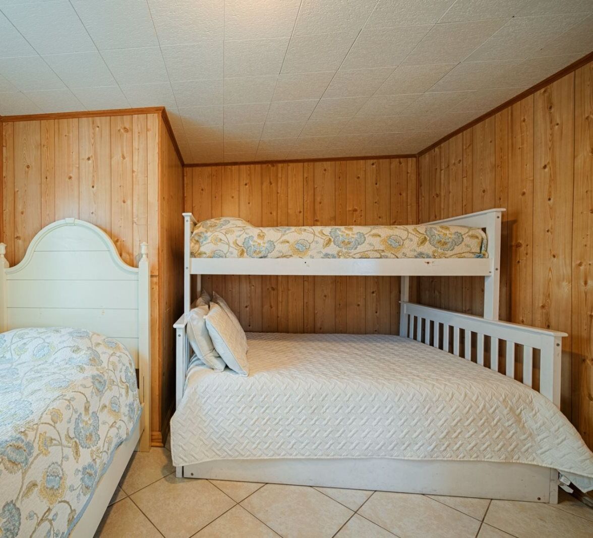 A bunk bed room with wooden walls and a tiled floor.