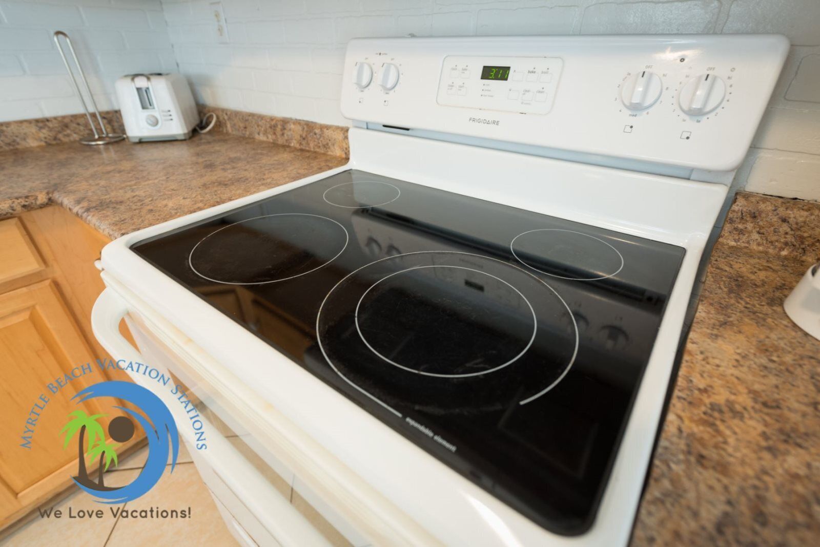 A kitchen with a white stove, granite countertop, and wooden cabinets.