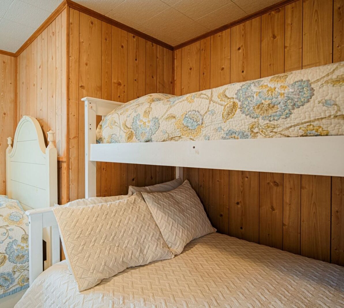 Una cama litera con un colchón superior estampado con motivos florales y un colchón inferior acolchado liso.