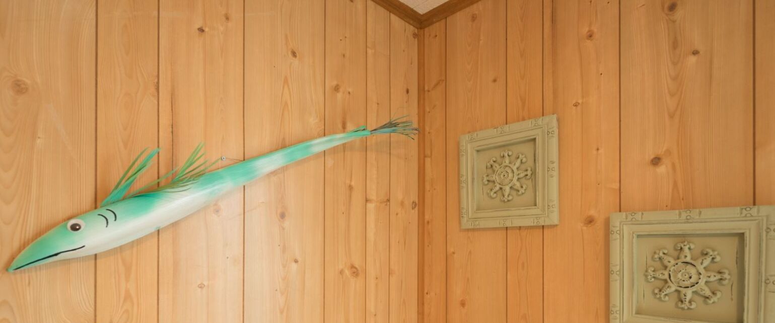 Une pièce aux murs en bois, décorée d’un motif de poisson et agrémentée de deux assiettes décoratives.