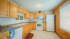 Uma cozinha compacta com armários de madeira, micro-ondas, fogão e refrigerador.