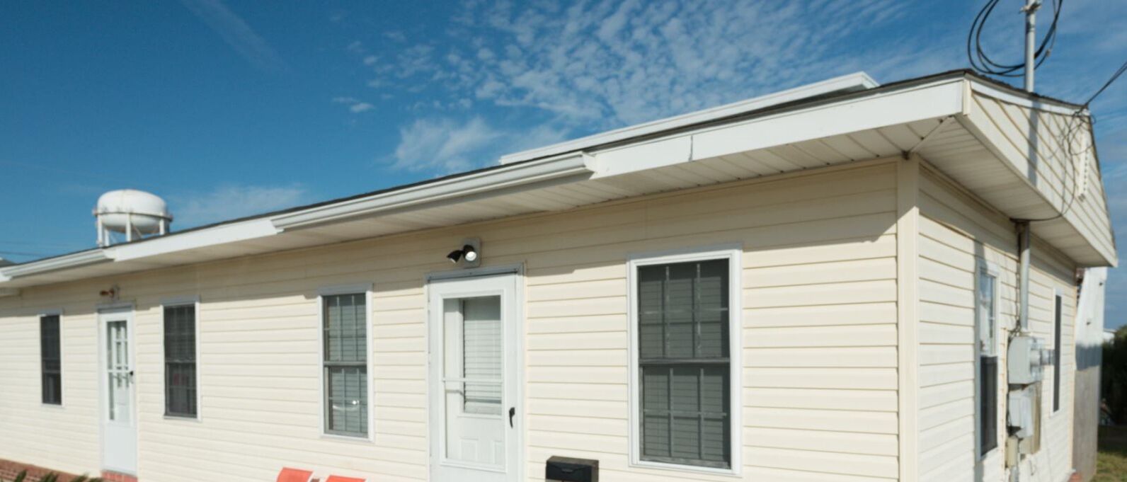 A single-story building with a flat roof, a water tank on the roof, and a white door.