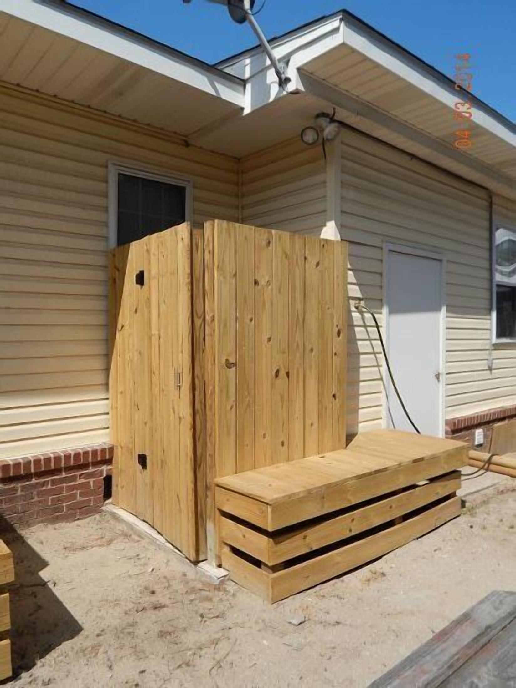 A wooden deck with a bench and a wooden fence in front of a house with siding and a garage.