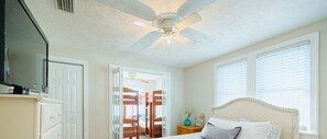 A bedroom with a bed, a ceiling fan, a TV, and a wardrobe. - CG Cottage Up (North Myrtle Beach)