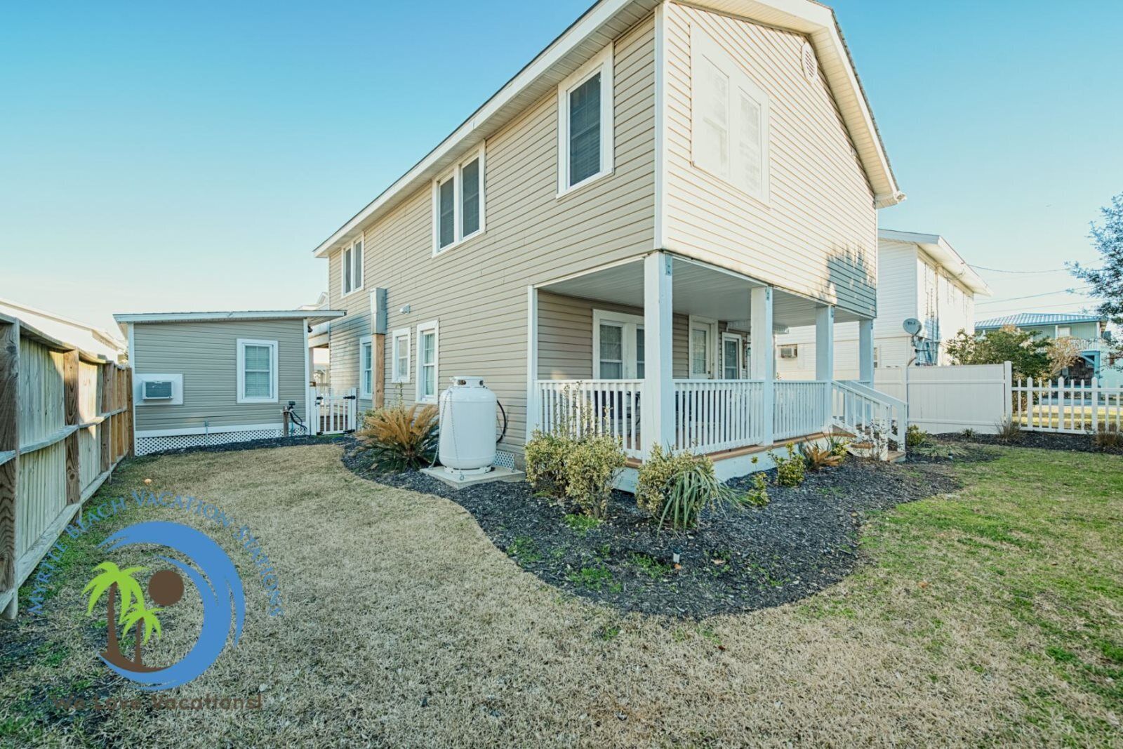A two-story house with a covered porch and a fenced backyard.