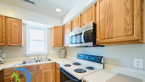 A kitchen with wooden cabinets, a microwave, a stove, and a sink. - Windy Hill Villa 2 - Beach Retreat (North Myrtle Beach)