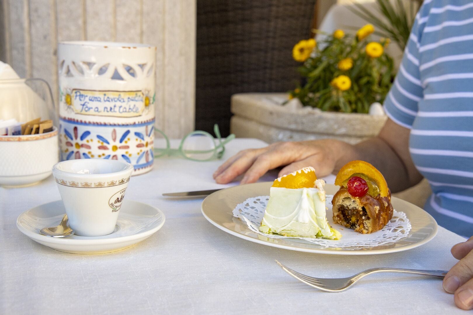 A dining table with a plate of food, a cup, and a decorative mug.