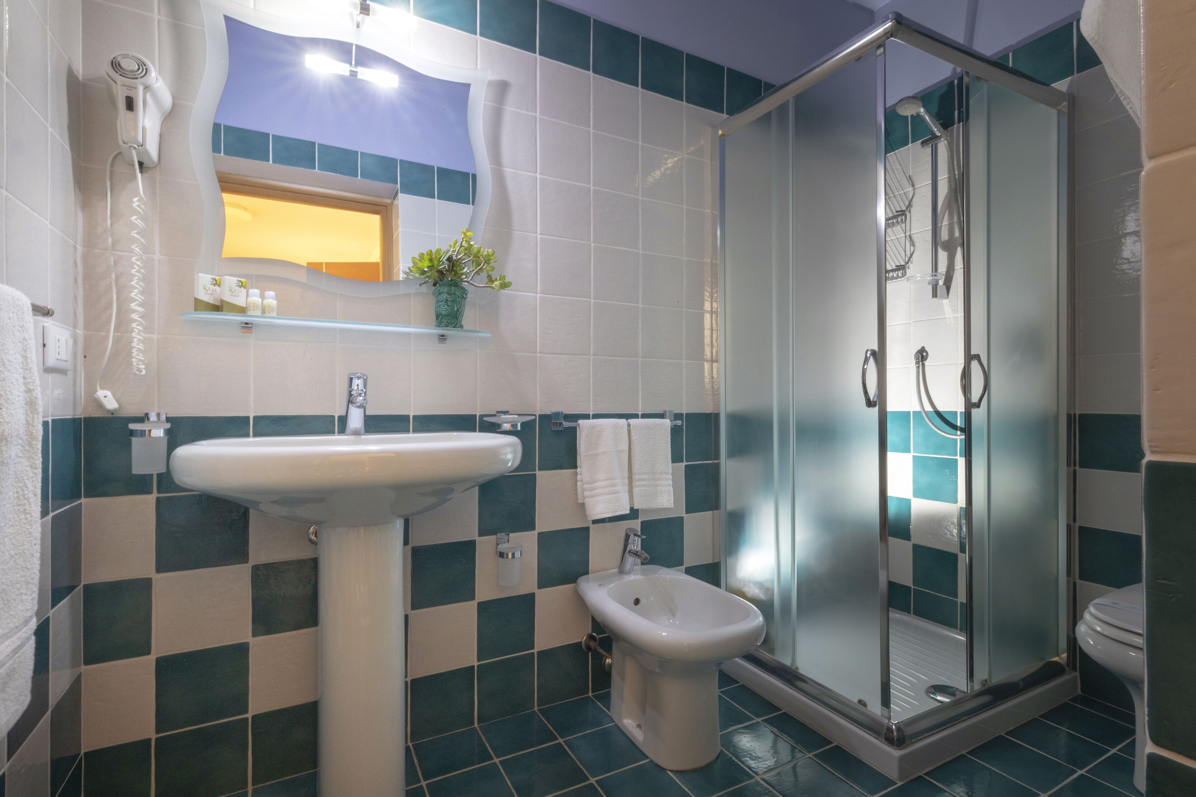 A bathroom with a sink, bidet, and shower.