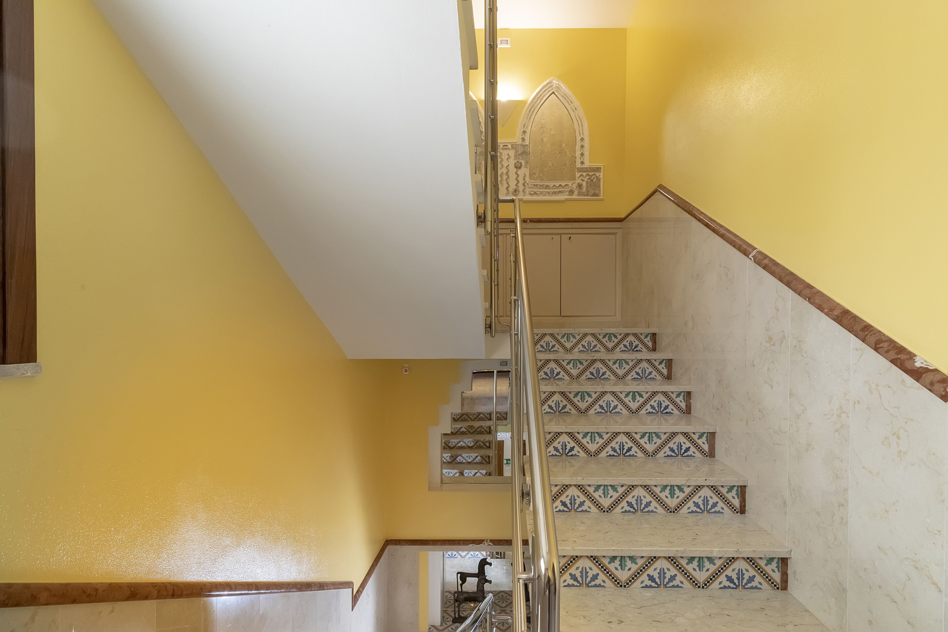 A staircase with patterned tiles and a metal handrail.