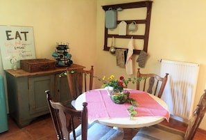 Un comedor con una mesa preparada para dos, un aparador de estilo vintage y un tendedero de pared.
