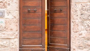 A wooden double door with a metal latch, set in a stone wall with a number '19' visible. - Room En Suite Corte Assisi (Assisi)