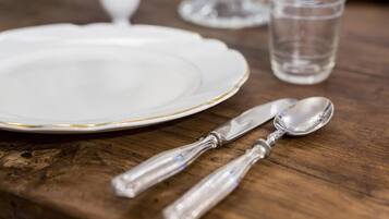 Une table en bois avec une assiette blanche, un couteau et une cuillère.