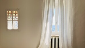 A room with a bed, a window with stained glass, and sheer curtains. - Room En Suite Corte Assisi (Assisi)