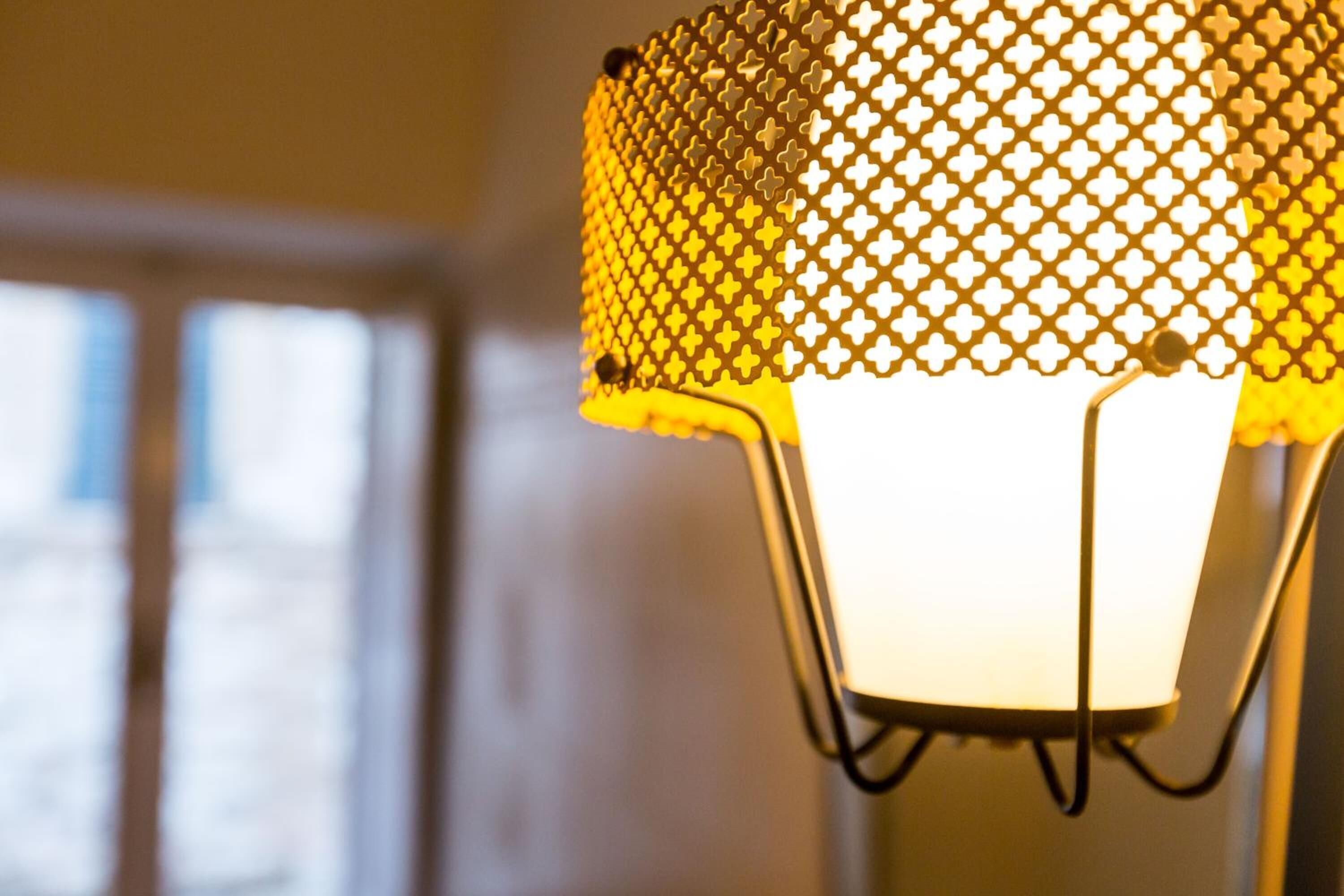 Ein Detailbild einer Lampe mit einem Gitter-Schirm und einem weißen Fuß.