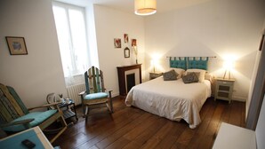A bedroom with a bed, bedside tables, a chair, a window, and a fireplace. - Chambres d'Hotes Ene Gutizia (Ustaritz)