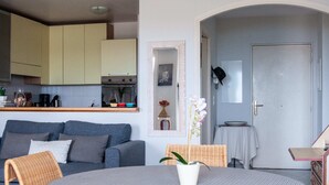 Un salon moderne avec un canapé gris, une table ronde et une orchidée en pot.