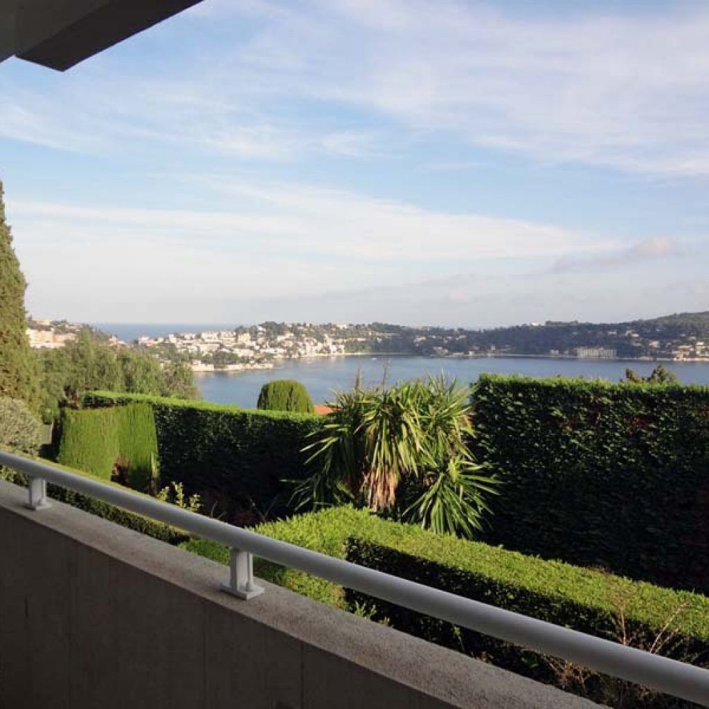 Ein Balkon mit Blick auf eine Küstenstadt und das Meer.