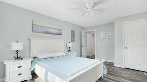 Ein Schlafzimmer mit einem Bett, Nachttischen, einem Deckenventilator und einer Tür.