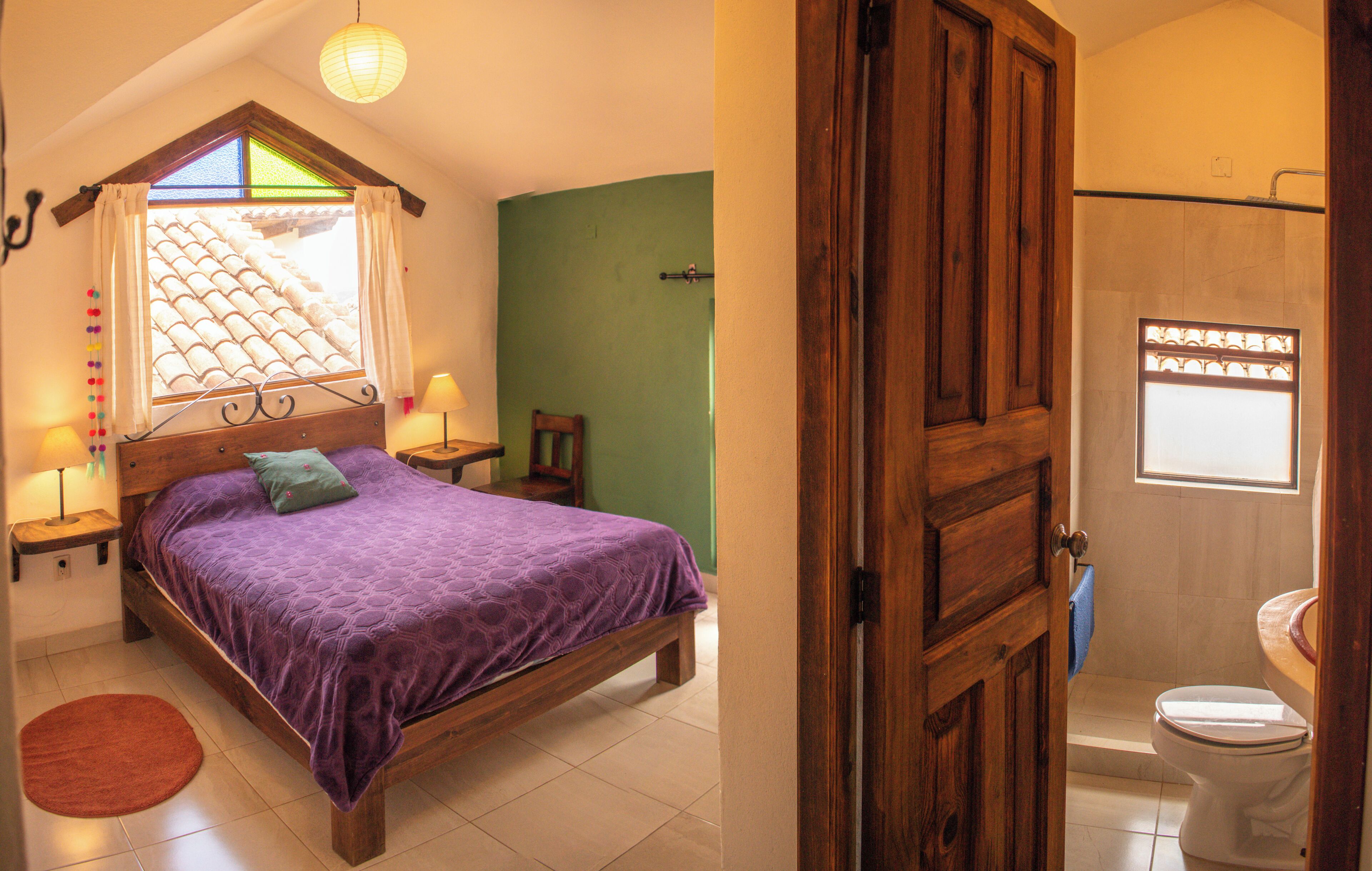 Un dormitorio con cama, ventana con cortinas, mesita de noche y lámpara de noche.