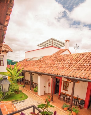 A courtyard with a tiled roof, a covered seating area, and potted plants. - Casa Tequio (San Cristobal de las Casas)