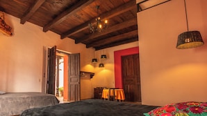 Una habitación con dos camas, techo de madera, puerta roja y una mesa con sillas.