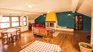 Una sala de estar acogedora con chimenea, muebles de madera y un comedor con mantel a cuadros.