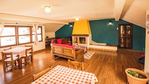 Una sala de estar acogedora con chimenea, muebles de madera y un comedor con mantel a cuadros.