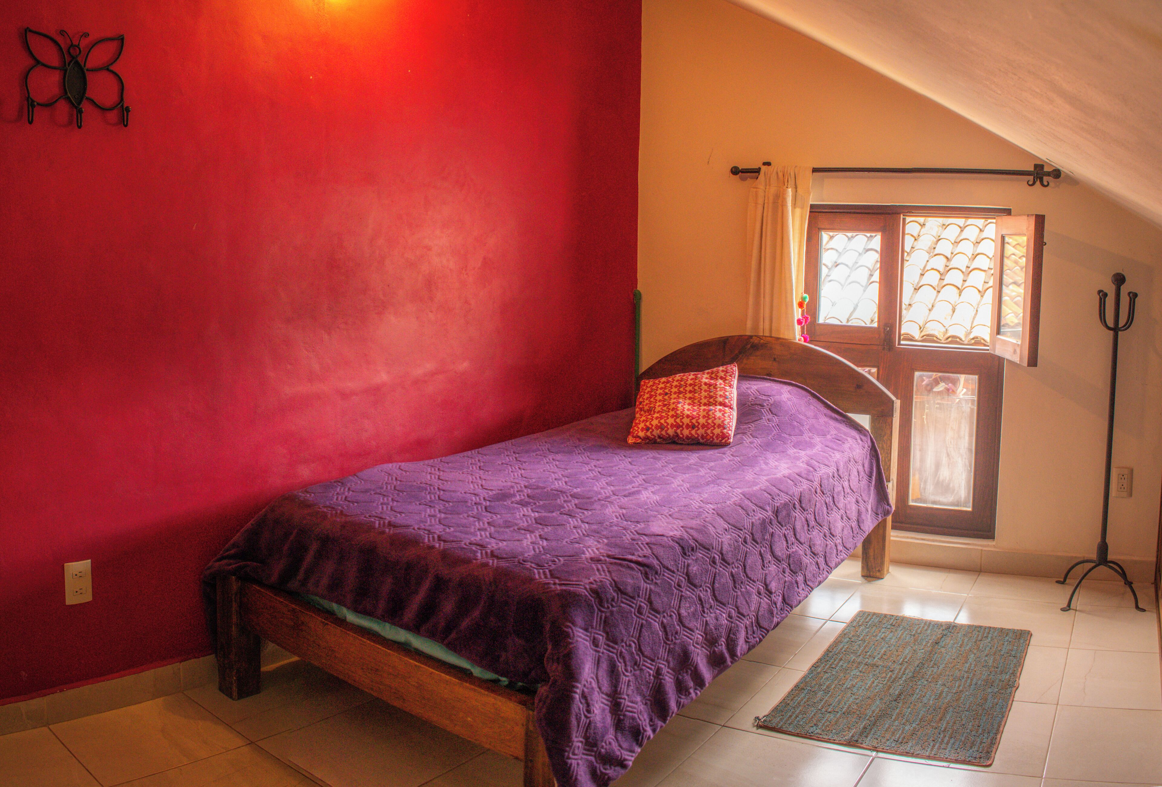 Un dormitorio con una cama, una ventana con cortinas, una lámpara de pie y una decoración de mariposa en la pared.