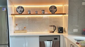 A modern kitchen with a stainless steel dishwasher, a coffee maker, and a toaster on the counter.